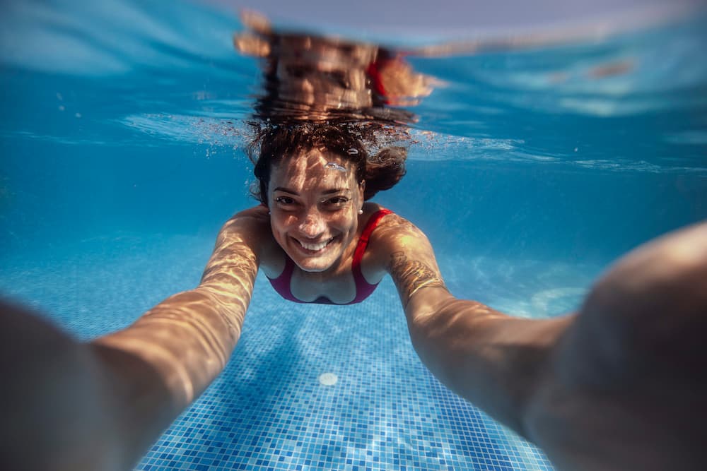 Frau schwimmt mit Kontaktlinsen im Pool und informiert sich über Risiken beim Schwimmen mit Kontaktlinsen
